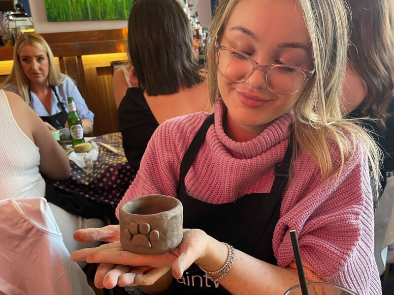 A woman is holding a handmade clay pot 